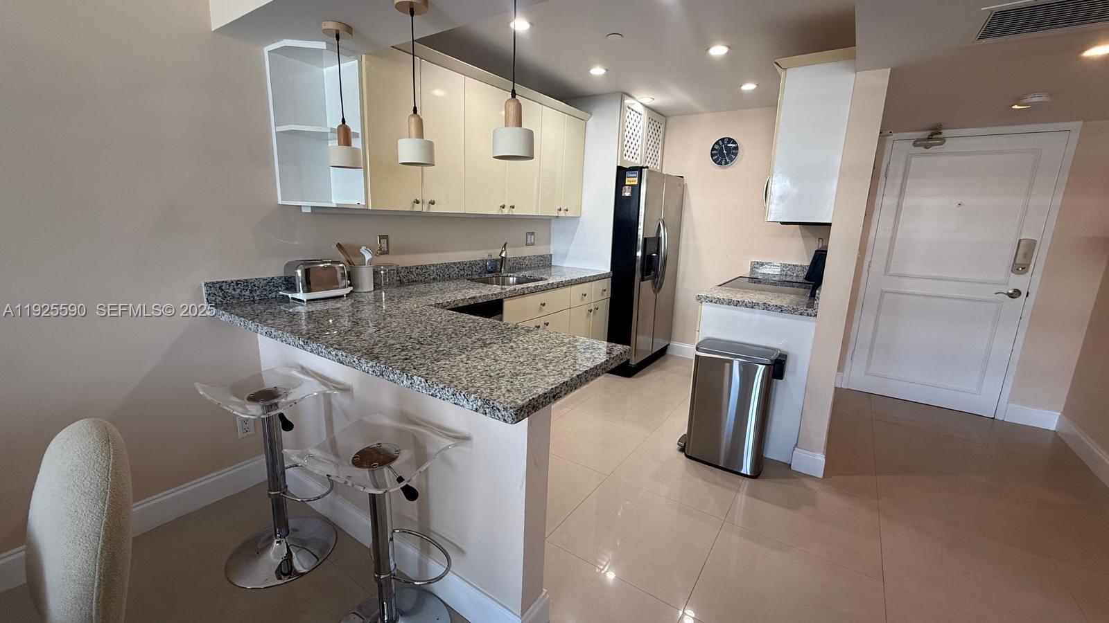 A kitchen features granite countertops, light-colored cabinetry, stainless steel appliances, and a breakfast bar — 100 Lincoln Rd # 1108, Miami Beach FL 33139, MIAMI BEACH, FL