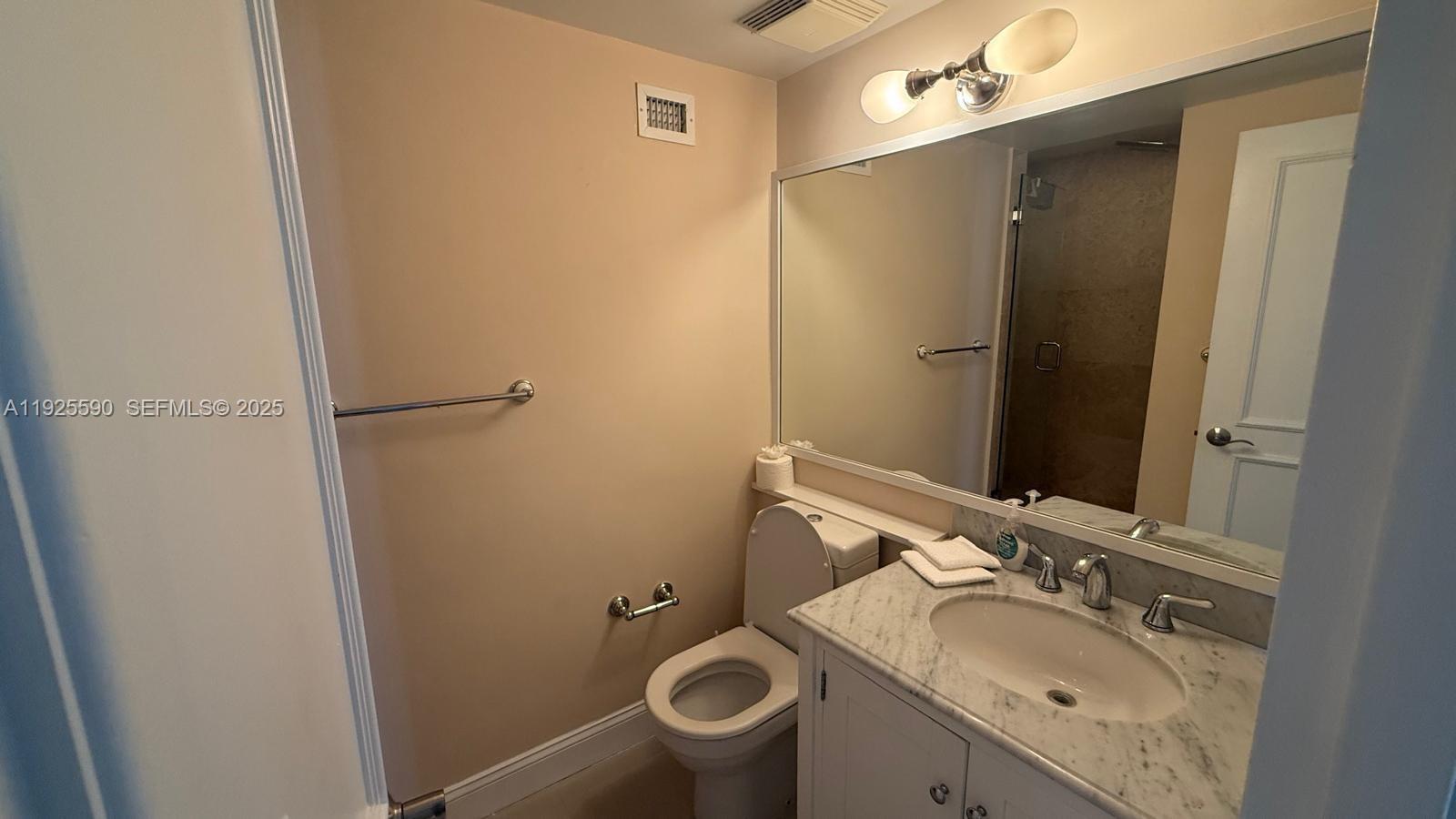 A bathroom features a white vanity with a marble countertop, a toilet, and a mirror — 100 Lincoln Rd # 1108, Miami Beach FL 33139, MIAMI BEACH, FL