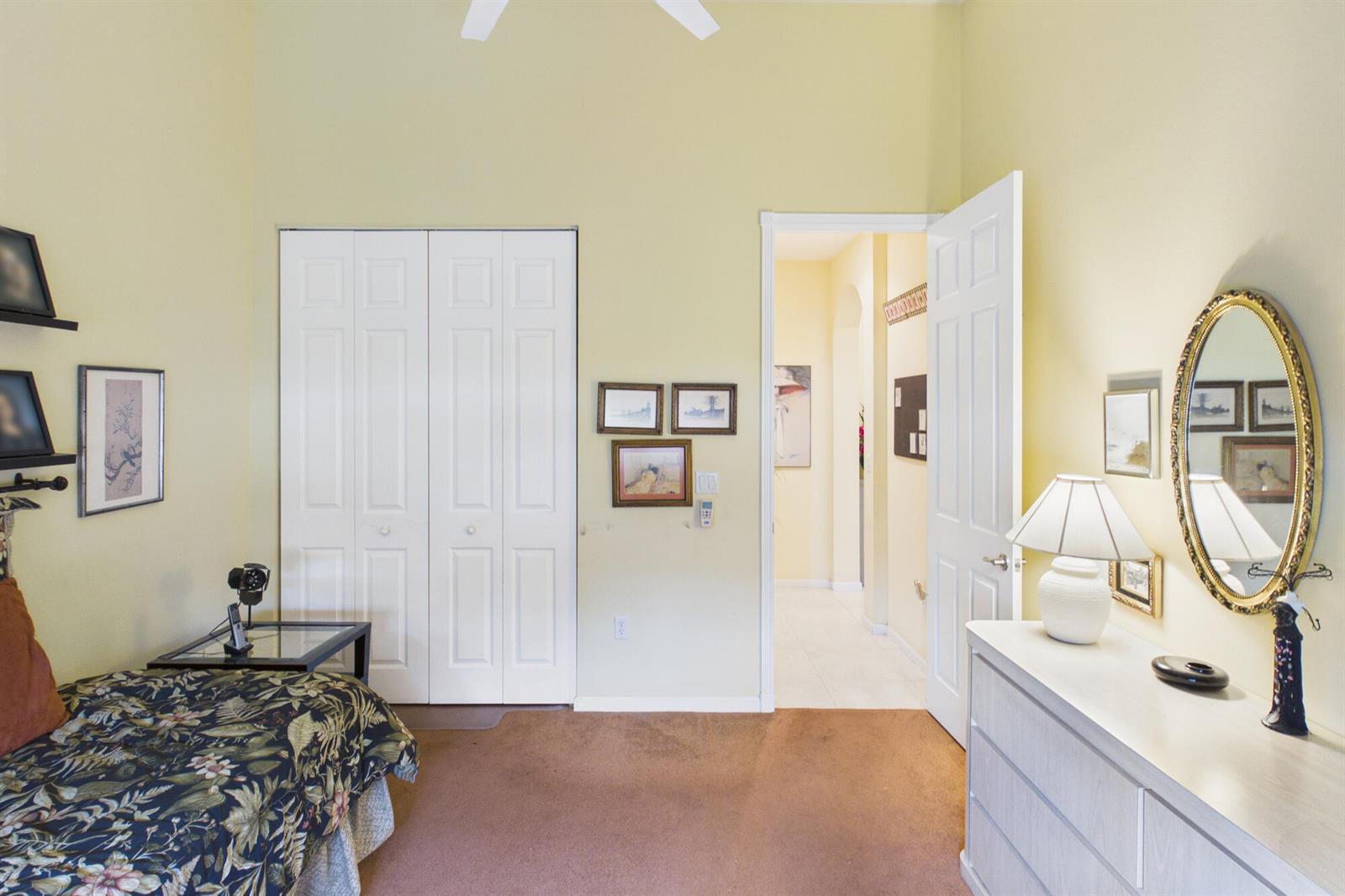 A bedroom with a bed, a dresser with a mirror, and a doorway to a hallway — 7159 Boscanni Drive, Boynton Beach FL 33437, BOYNTON BEACH, FL