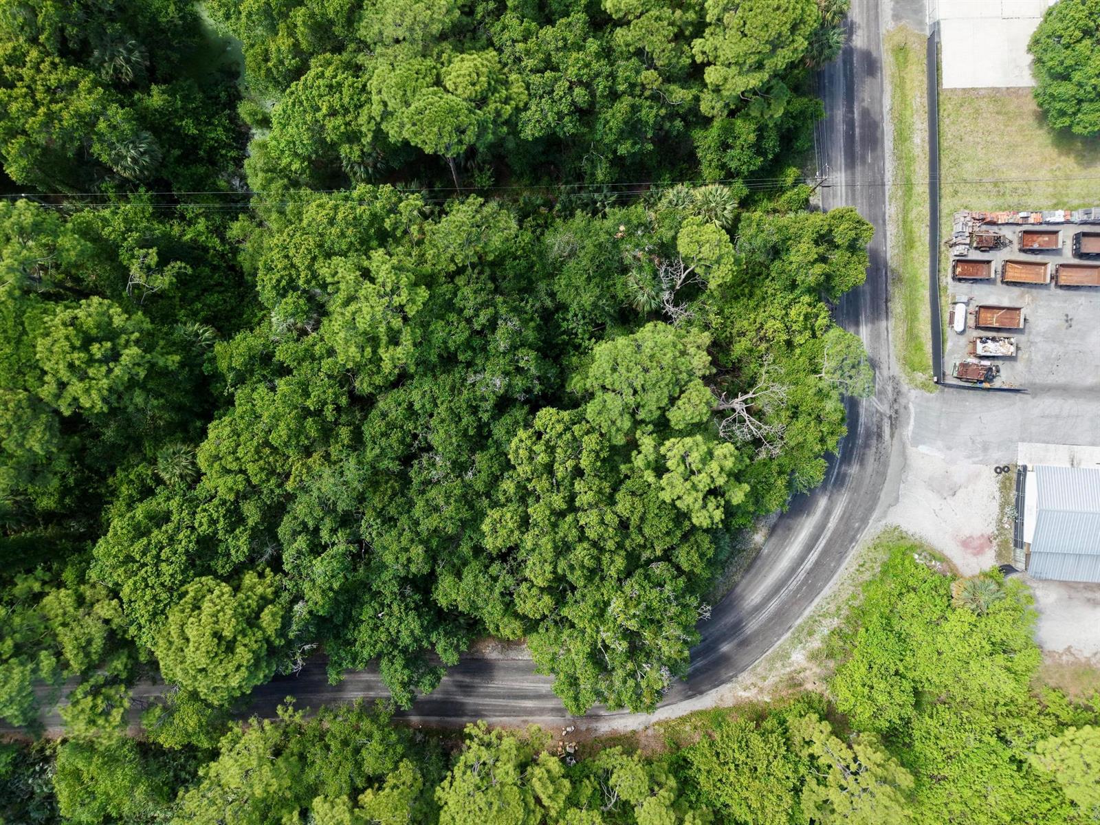 An aerial view shows a curved road bordering a dense forest and a storage lot — 0000 Notlem Drive, Fort Pierce FL 34982, FORT PIERCE, FL