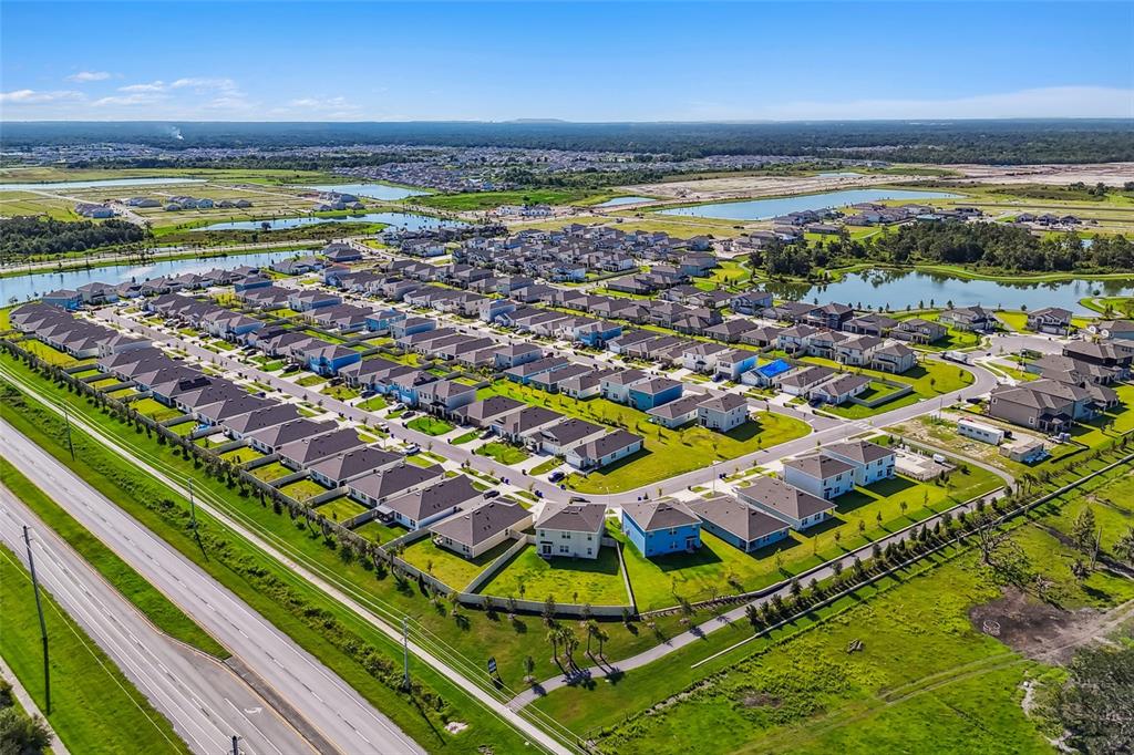 An aerial view shows a suburban residential neighborhood with many houses near a large pond — 5603 FREESIA DRIVE, LAKELAND, FL