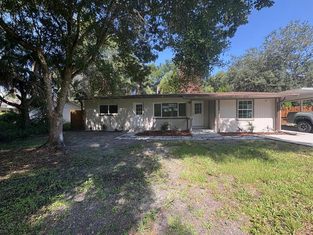 A single-story house with a beige exterior, a covered entryway, and a large shade tree — 4358 BEDFORD ROAD, SANFORD, FL