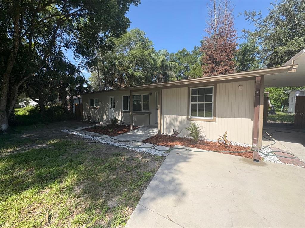 A single-story house with beige vertical siding, a concrete driveway, and a covered entryway — 4358 BEDFORD ROAD, SANFORD, FL