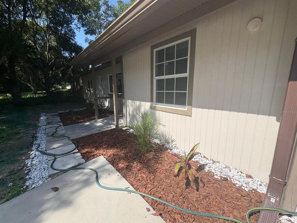 A side view of a house exterior featuring vertical siding, a window, and a walkway — 4358 BEDFORD ROAD, SANFORD, FL