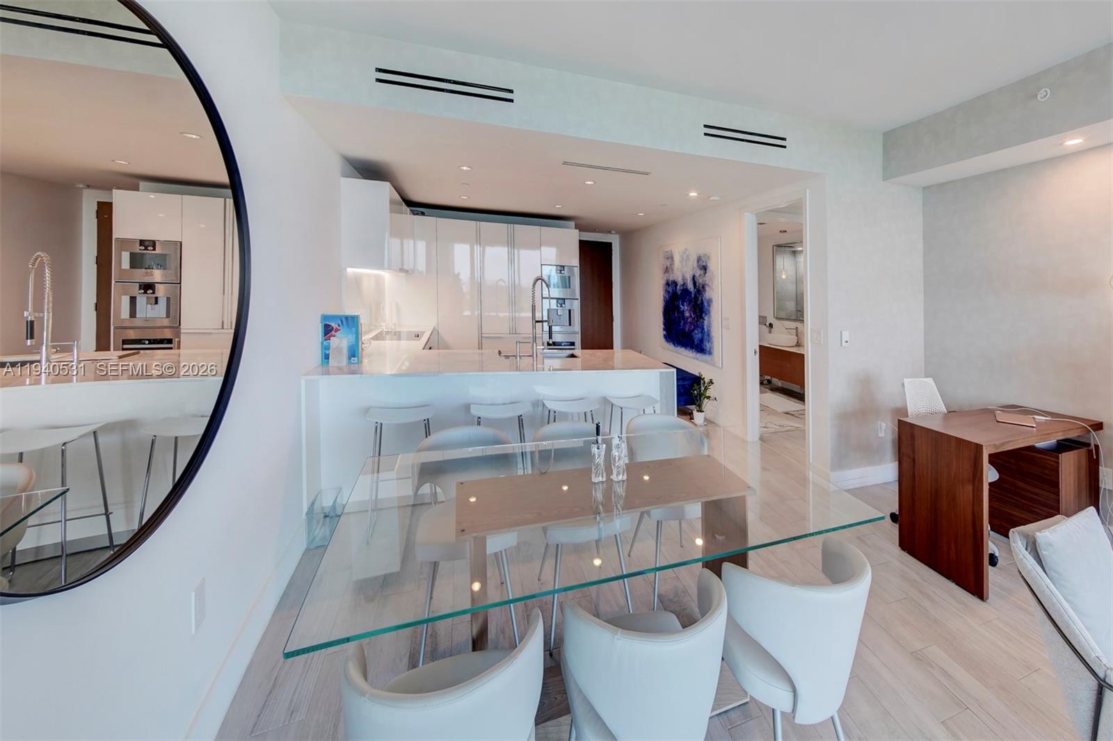 A modern kitchen with white cabinetry and a glass dining table in an open-concept room — 10201 Collins Ave # 804, Bal Harbour FL 33154, BAL HARBOUR, FL