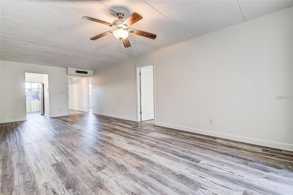 An empty room features wood-look flooring, a ceiling fan, and white walls — 4435 1ST STREET NE UNIT 111, ST PETERSBURG, FL