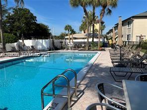 A swimming pool with lounge chairs and palm trees at a residential complex — 4000 Crystal Lake Dr # 111, Deerfield Beach FL 33064, DEERFIELD BEACH, FL