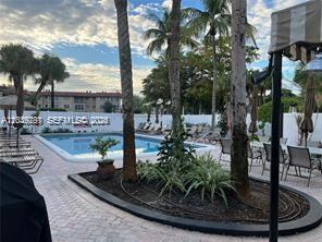A swimming pool sits in a courtyard surrounded by palm trees and lounge chairs — 4000 Crystal Lake Dr # 111, Deerfield Beach FL 33064, DEERFIELD BEACH, FL