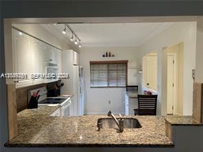 A kitchen features granite countertops, white cabinetry, a sink, and a window overlooking a dining area — 4000 Crystal Lake Dr # 111, Deerfield Beach FL 33064, DEERFIELD BEACH, FL
