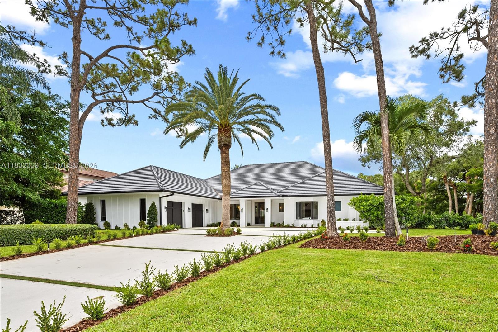 A single-story white house with a dark tiled roof and a palm tree-lined driveway — 1761 Breakers West Blvd, West Palm Beach FL 33411, WEST PALM BEACH, FL