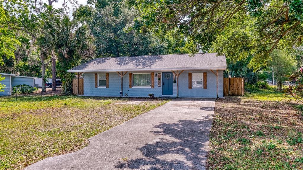 A single-story light blue brick house with a concrete driveway and wooden porch supports — 2122 LAKE BOULEVARD, WINTER HAVEN, FL
