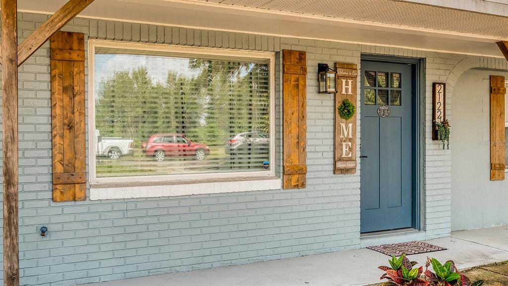 A light blue brick house exterior features a large window, wooden shutters, and a blue door — 2122 LAKE BOULEVARD, WINTER HAVEN, FL