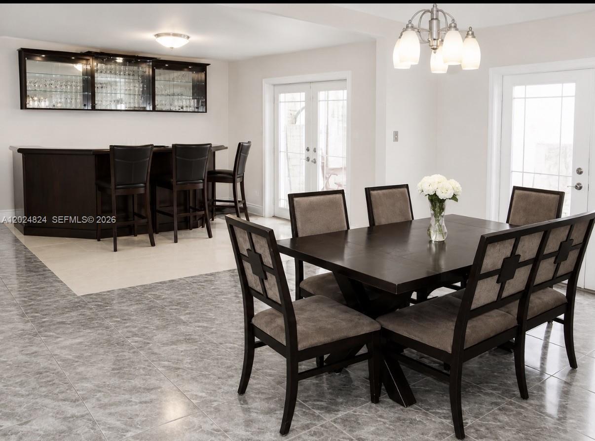 A dining area with a dark wood table and chairs adjacent to a home bar — 15530 SW 155th Ave, Miami FL 33187, MIAMI, FL