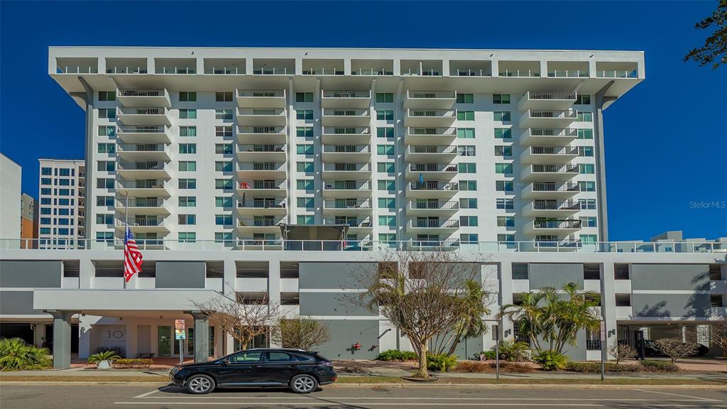 A multi-story white apartment building features balconies and a ground-level parking garage — 101 S GULFSTREAM AVENUE UNIT 4J, SARASOTA, FL
