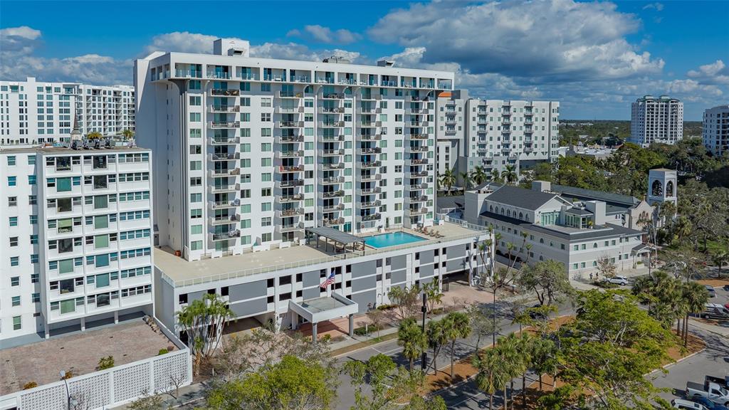 An aerial view shows a tall white apartment building with a pool and parking garage — 101 S GULFSTREAM AVENUE UNIT 4J, SARASOTA, FL