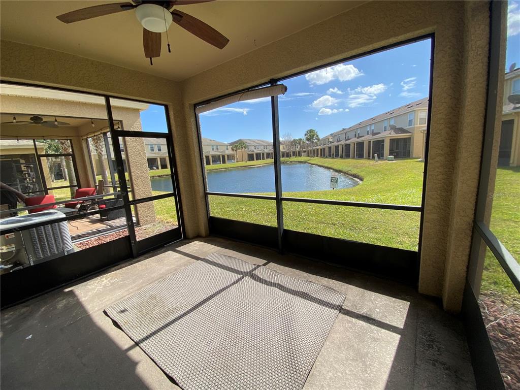 A screened-in patio features a concrete floor, a ceiling fan, and a view of a pond — 4658 69TH PLACE NORTH, PINELLAS PARK, FL