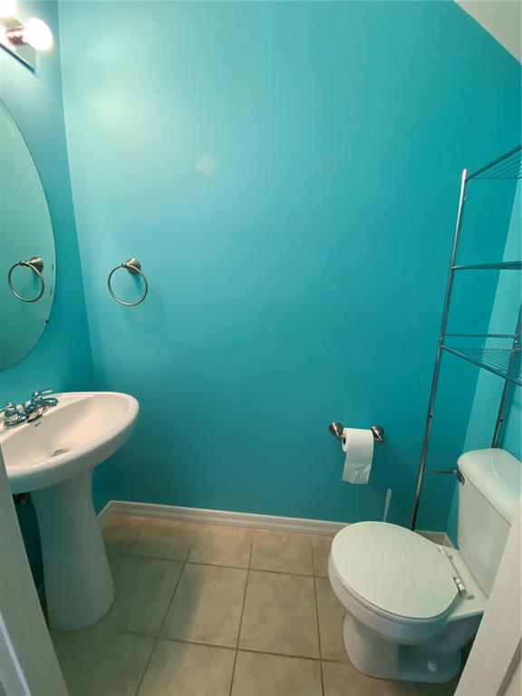 A small bathroom features bright blue walls, a pedestal sink, and a white toilet — 4658 69TH PLACE NORTH, PINELLAS PARK, FL