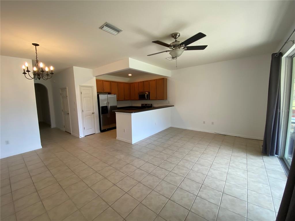 An open-concept living and dining area features tile flooring, a ceiling fan, and a kitchen — 4658 69TH PLACE NORTH, PINELLAS PARK, FL
