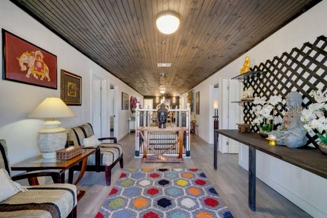 A hallway features a wood-paneled ceiling, a colorful geometric rug, and Asian-inspired decor — 209 W OLYMPIA AVENUE, PUNTA GORDA, FL