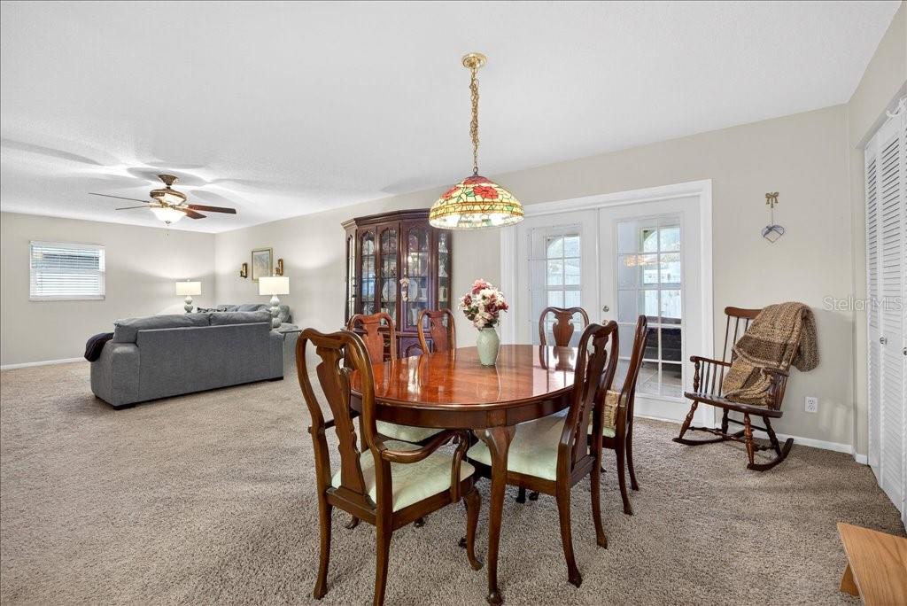 A dining room features a wooden table, chairs, a stained-glass pendant light, and carpeted floors — 46 FLEMING COURT, PALM COAST, FL