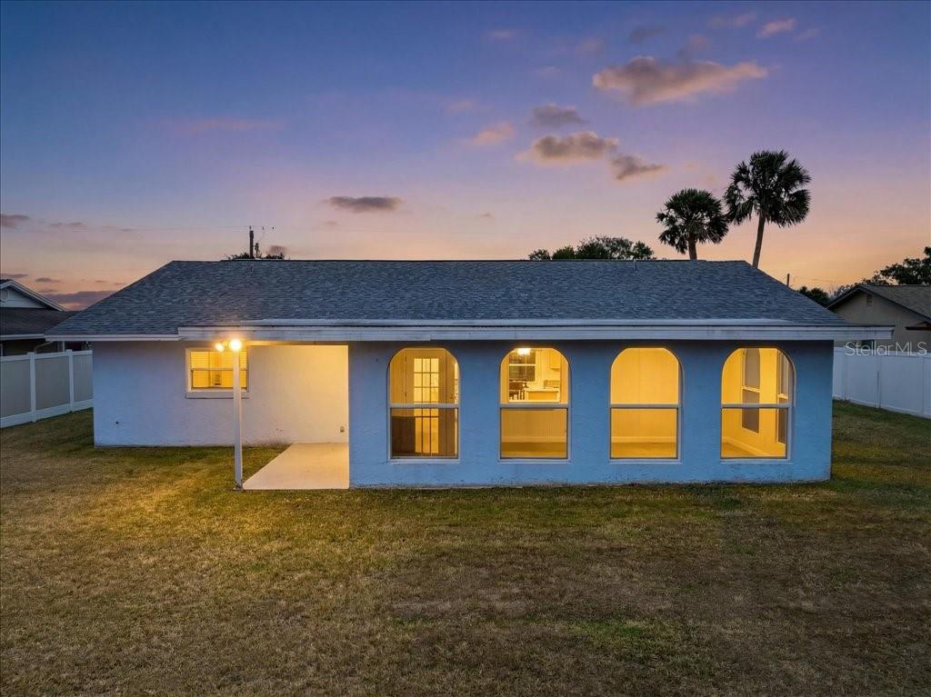 The exterior of a light blue house features a covered patio and four arched windows — 46 FLEMING COURT, PALM COAST, FL