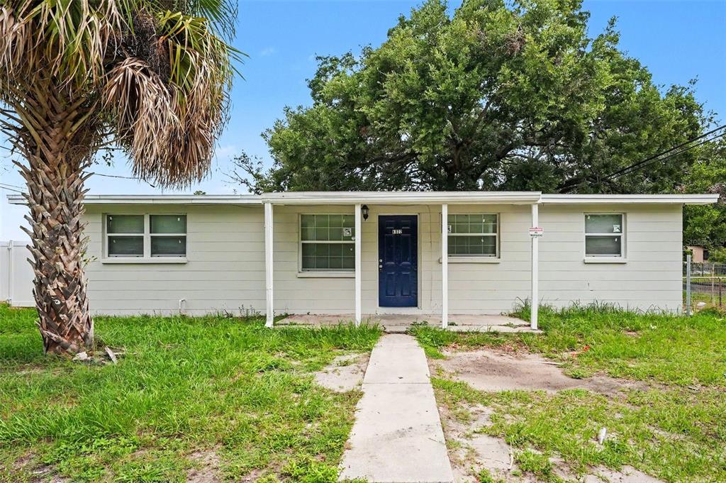 A single-story house with light-colored siding, a blue front door, and a concrete walkway — 4022 E HENRY AVENUE, TAMPA, FL