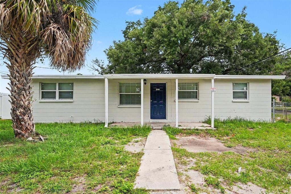 A single-story house with light-colored siding, a blue front door, and a concrete walkway — 4022 E HENRY AVENUE, TAMPA, FL