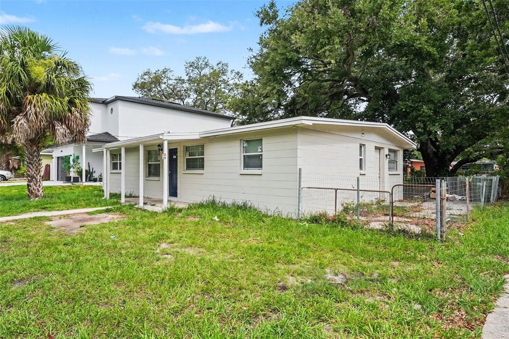A single-story white house with a covered porch and a chain-link fenced yard — 4022 E HENRY AVENUE, TAMPA, FL