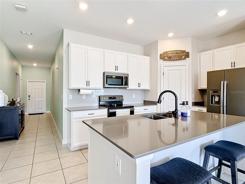 A kitchen features white cabinets, gray countertops, a center island, and stainless steel appliances — 237 TAFT DRIVE, DAVENPORT, FL