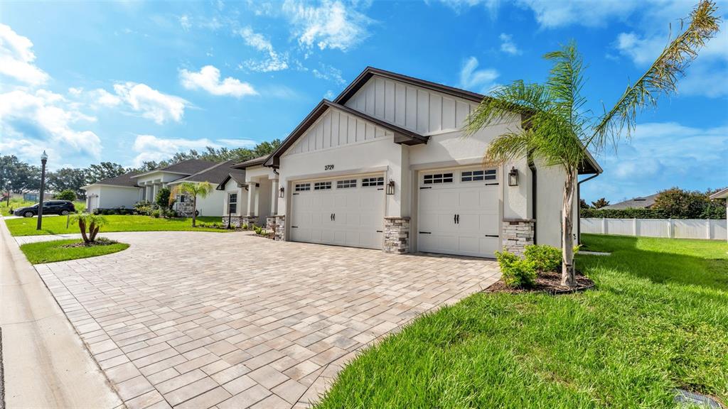 A single-story house with a paved driveway, two-car garage, and a palm tree in front — 2729 SUNRISE LANDING LANE, LAKELAND, FL