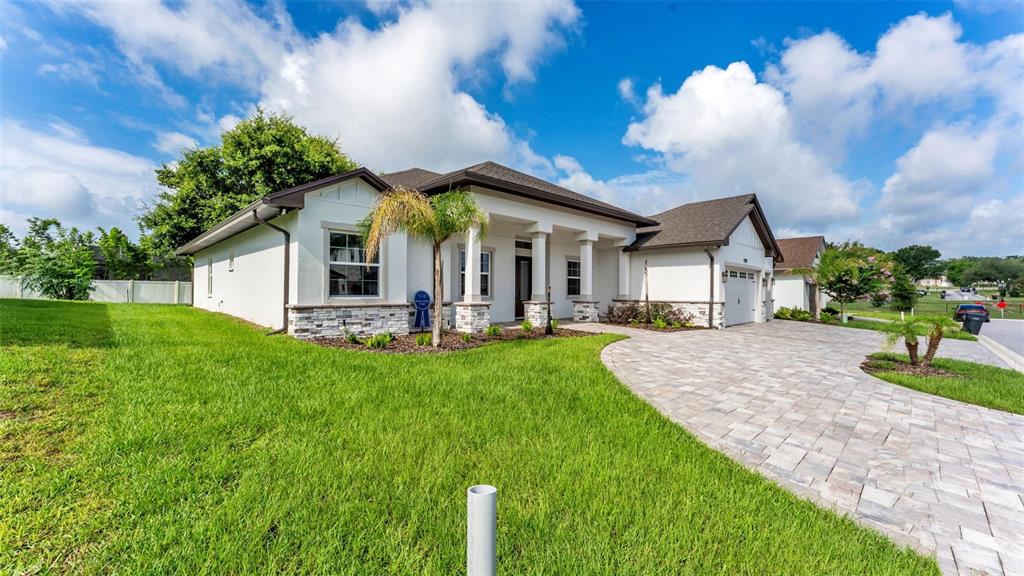 A single-story house with white stucco walls, stone accents, and a paved driveway — 2729 SUNRISE LANDING LANE, LAKELAND, FL