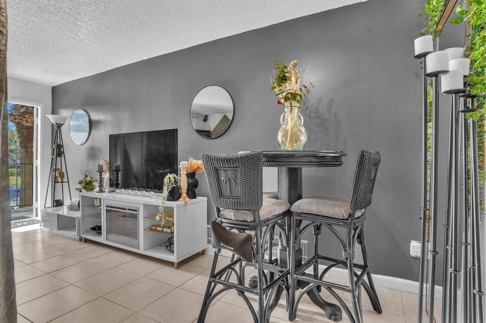 A living room features a gray accent wall, a white media console, and a bistro set — 1423 Meadows Circle W, Boynton Beach FL 33436, BOYNTON BEACH, FL