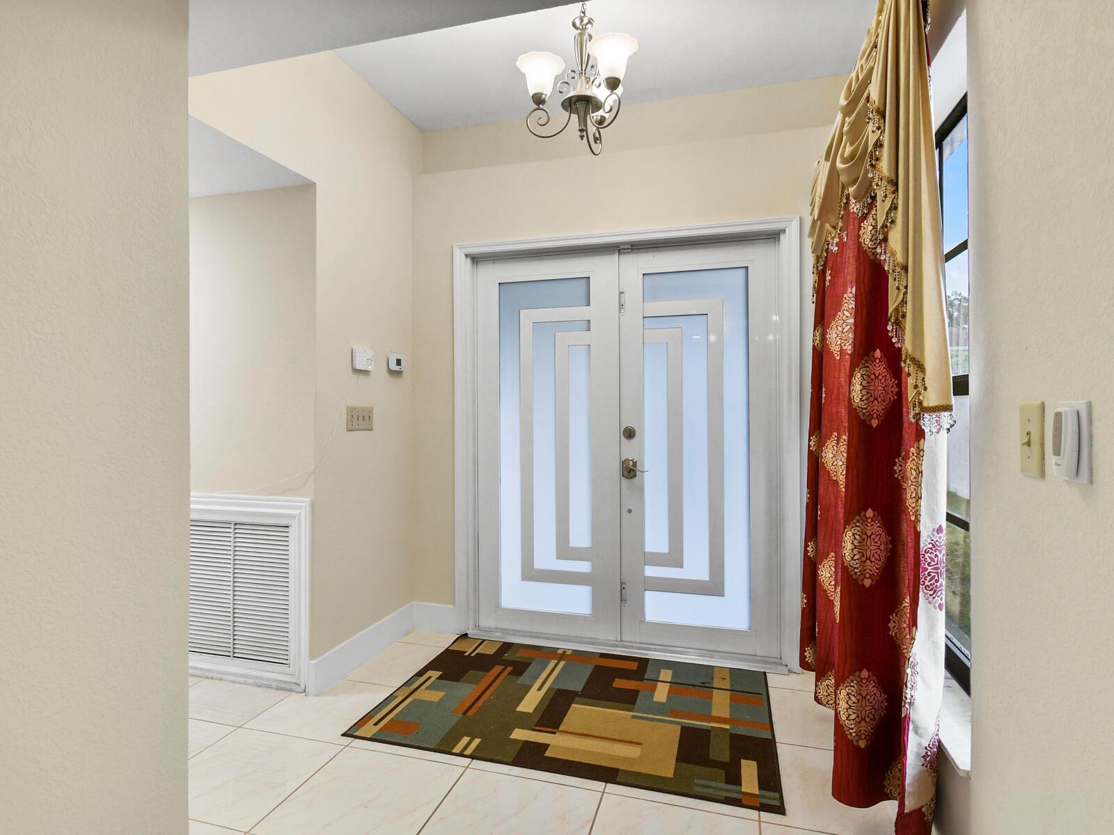 An entryway features a double door with geometric glass, a chandelier, and a patterned rug — 22965 Old Inlet Bridge Drive, Boca Raton FL 33433, BOCA RATON, FL