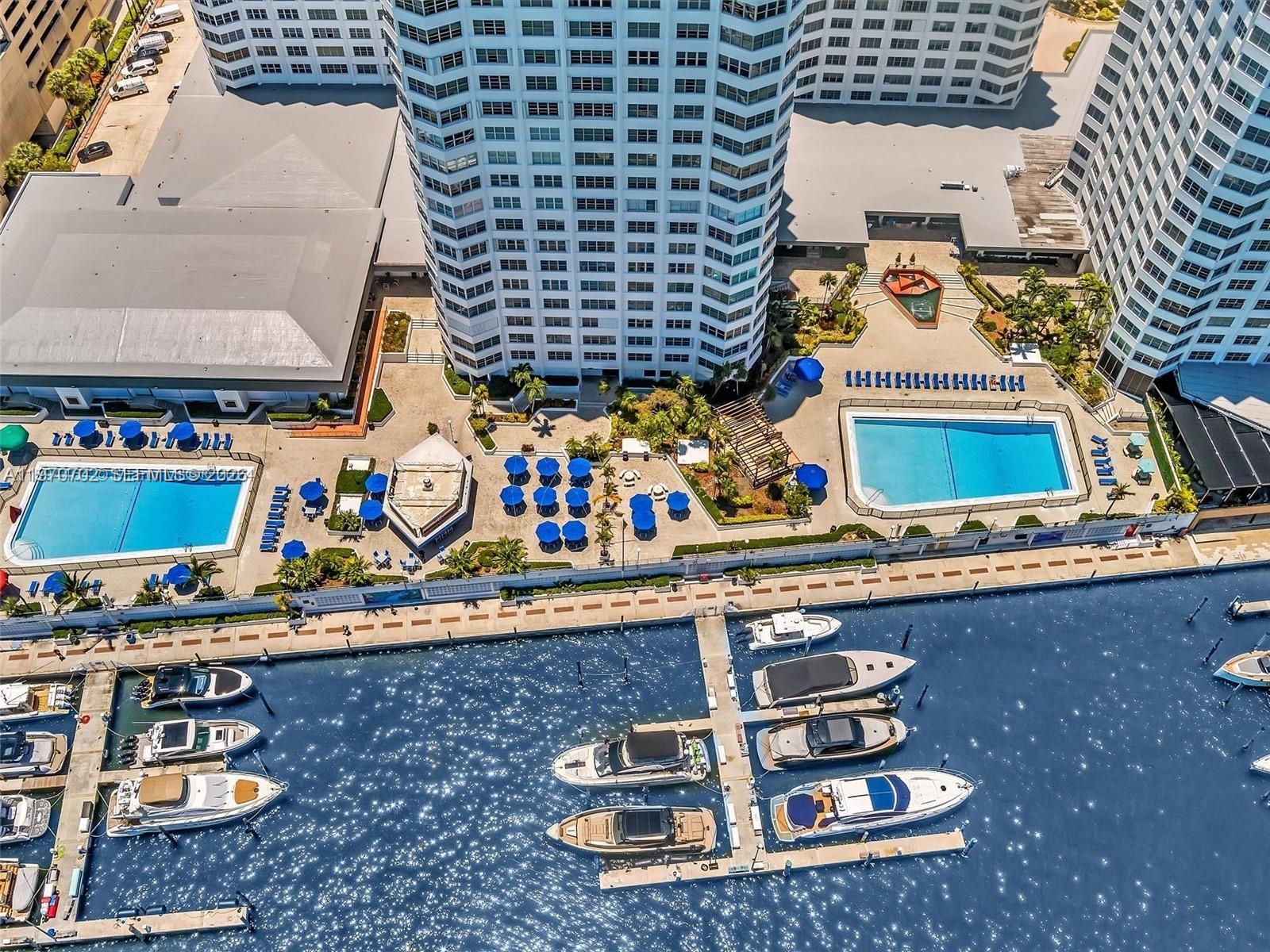 An aerial view shows a high-rise building with a pool deck and a private marina — 999 Brickell Bay Dr # 303, Miami FL 33131, MIAMI, FL