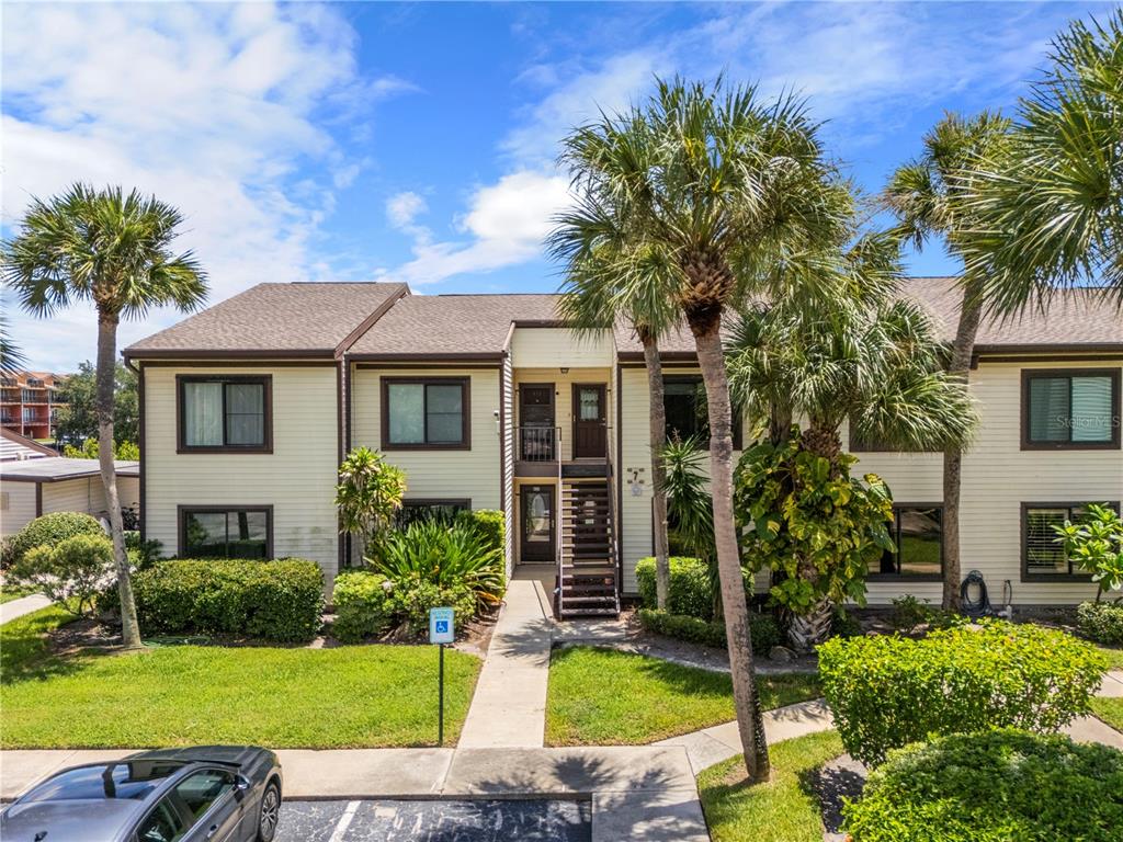 A two-story apartment building with beige siding, brown trim, and an exterior staircase — 428 MOORINGS COVE DRIVE UNIT 7F, TARPON SPRINGS, FL