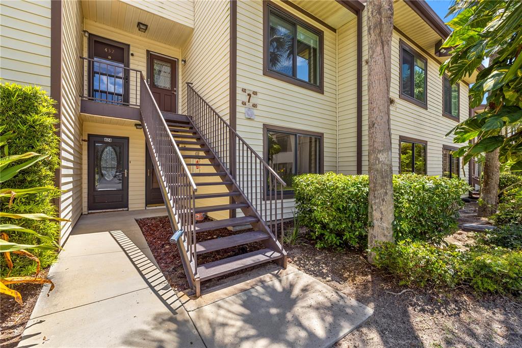 An exterior view of a two-story apartment building with a metal staircase leading to the second floor — 428 MOORINGS COVE DRIVE UNIT 7F, TARPON SPRINGS, FL