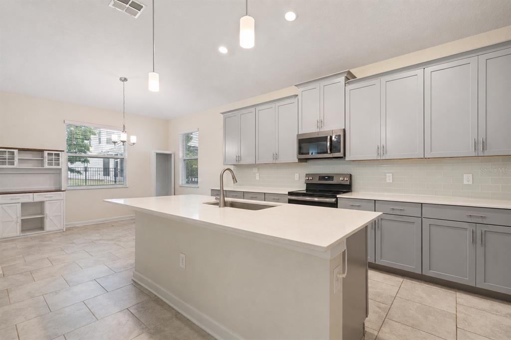 A kitchen with gray cabinets, white countertops, a center island, and light-colored tile flooring — 1478 OLYMPIC CLUB BOULEVARD, CHAMPIONS GATE, FL