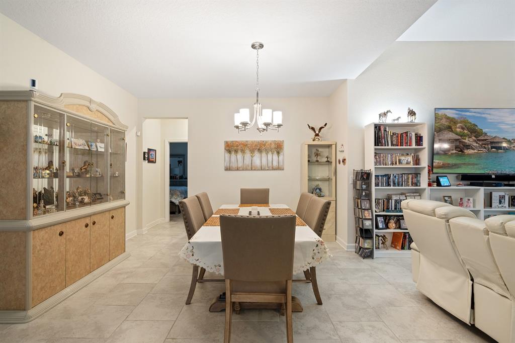 A dining room features a table with six chairs, a china cabinet, and a bookshelf — 1478 OLYMPIC CLUB BOULEVARD, CHAMPIONS GATE, FL