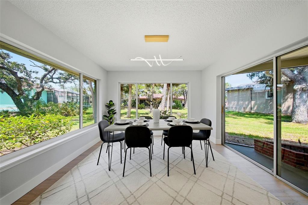 A dining room with a rectangular table, six black chairs, and large windows overlooking trees — 4301 MARINE PARKWAY, NEW PORT RICHEY, FL