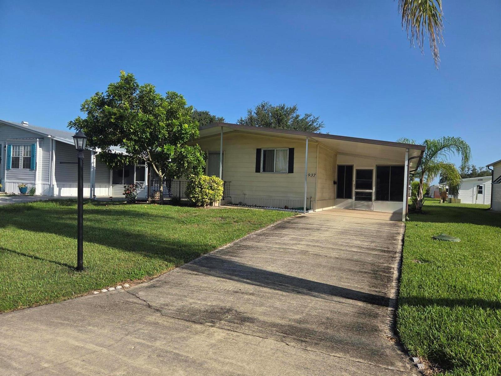 A single-story mobile home with a concrete driveway and a front lawn — 6937 SE Delegate Street, Hobe Sound FL 33455, HOBE SOUND, FL