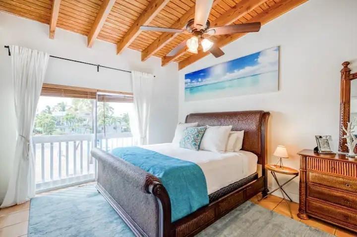 A bedroom features a wooden vaulted ceiling, a ceiling fan, and a view of trees — 164 Ocean Bay Drive # c, Key Largo FL 33037, KEY LARGO, FL