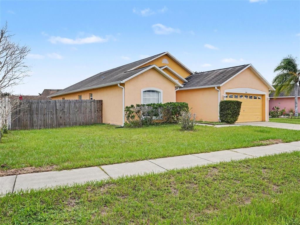 A single-story peach-colored house with a two-car garage and a wooden fence — 414 SPICE COURT, KISSIMMEE, FL