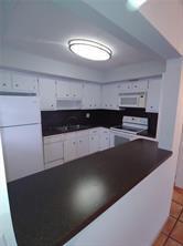 A kitchen features white cabinets, dark countertops, a white refrigerator, and a ceiling light fixture — 3720 Harrison Street # 3, Hollywood FL 33021, HOLLYWOOD, FL