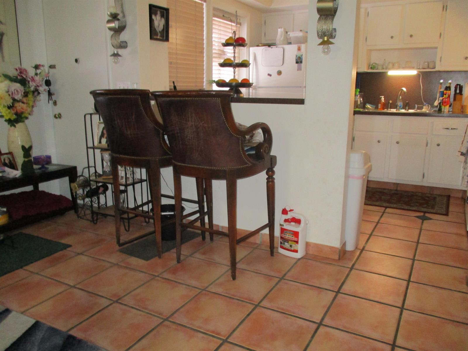 A kitchen with a breakfast bar, two leather stools, and terracotta tile flooring — 3720 Harrison Street # 3, Hollywood FL 33021, HOLLYWOOD, FL
