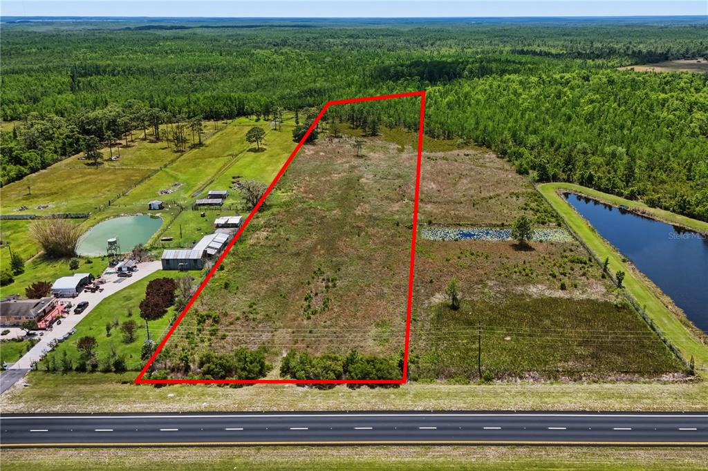 An aerial view shows a rectangular plot of land outlined in red beside a road — E IRLO BRONSON MEMORIAL HIGHWAY UNIT 0, ST CLOUD, FL