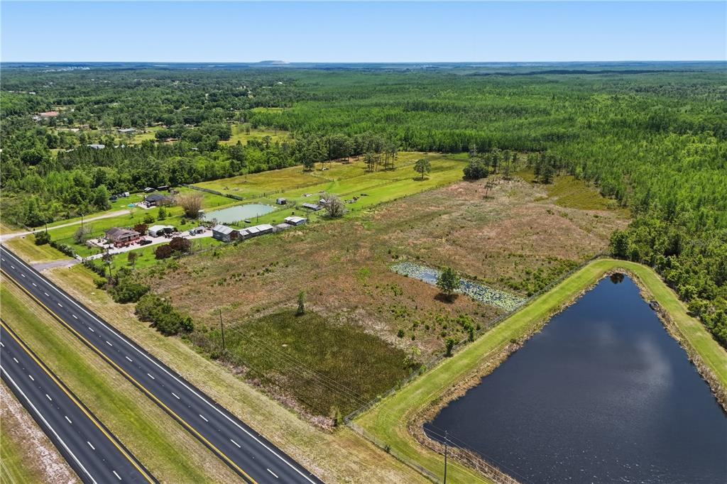 An aerial view shows a rural property with a house, outbuildings, and two ponds — E IRLO BRONSON MEMORIAL HIGHWAY UNIT 0, ST CLOUD, FL