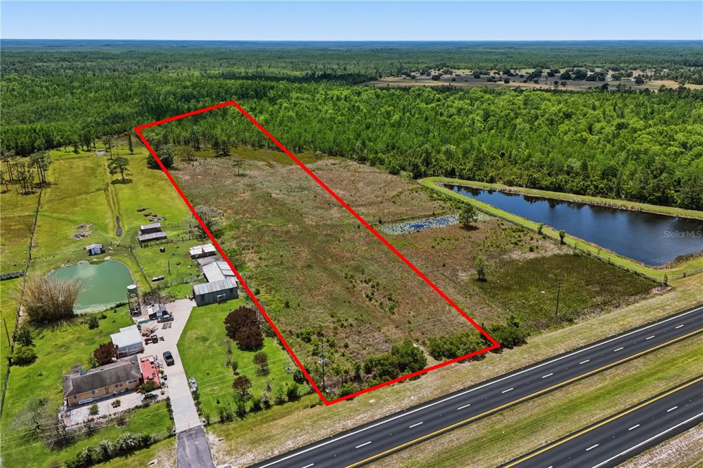 An aerial view shows a rectangular plot of land outlined in red beside a highway — E IRLO BRONSON MEMORIAL HIGHWAY UNIT 0, ST CLOUD, FL