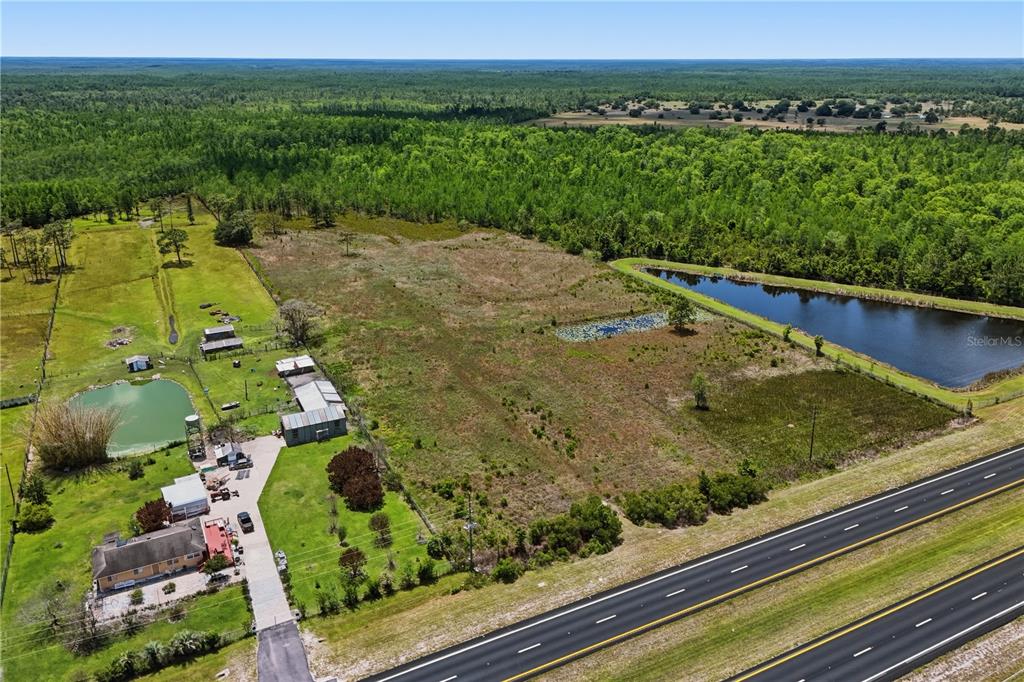An aerial view shows a house, outbuildings, two ponds, and open land beside a highway — E IRLO BRONSON MEMORIAL HIGHWAY UNIT 0, ST CLOUD, FL