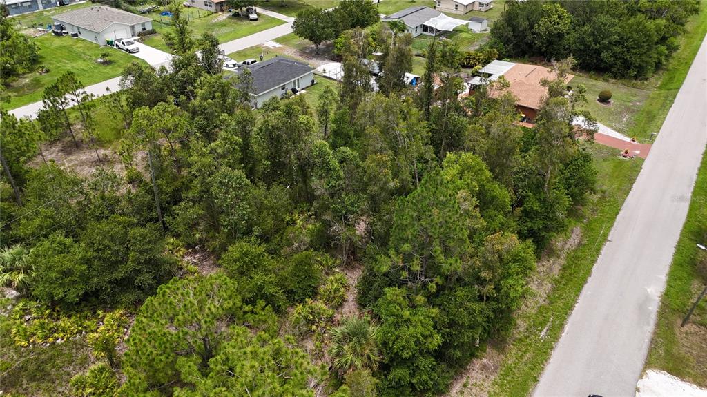 An aerial view shows a wooded, undeveloped residential lot situated between two houses and a road — 11317 4TH AVENUE, PUNTA GORDA, FL
