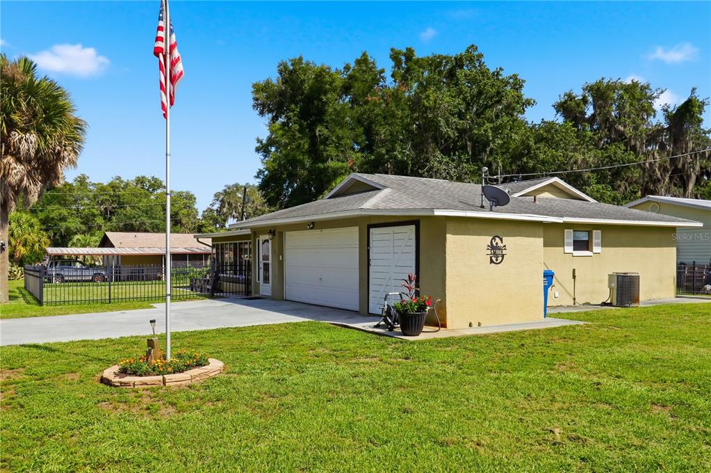 A tan house with a white garage door, a flag pole, and a fenced yard — 1381 CR 446A, LAKE PANASOFFKEE, FL